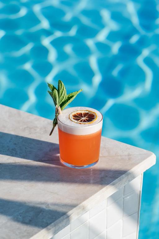 Kokteilis ar žāvētu apelsīnu pie Liberty Hotels Lara baseina.
