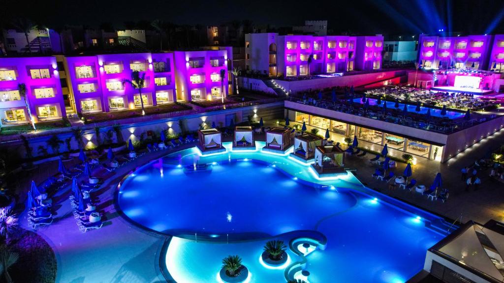 Nakts skats uz Cleopatra Luxury Resort Sharm - Adults Only ar izgaismotu baseinu.