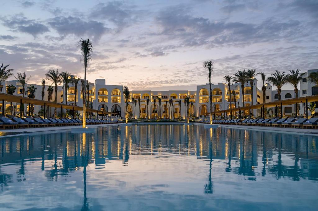 Serry Beach Resort piekrastes baseins ar palmām un nakts gaismu.