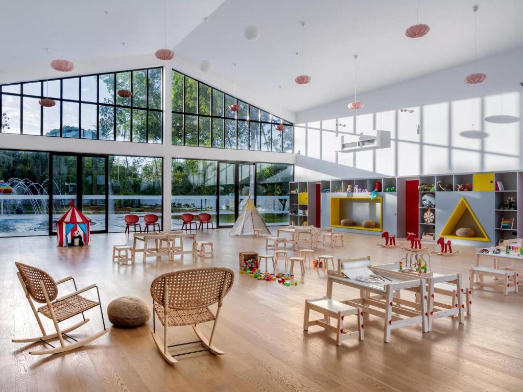 Mūsdienīga bērnu spēļu telpa ar daudzām rotaļlietām un vieglu, gaišu interjeru. Lielie logi nodrošina dabīgo apgaismojumu, radot patīkamu un draudzīgu atmosfēru.