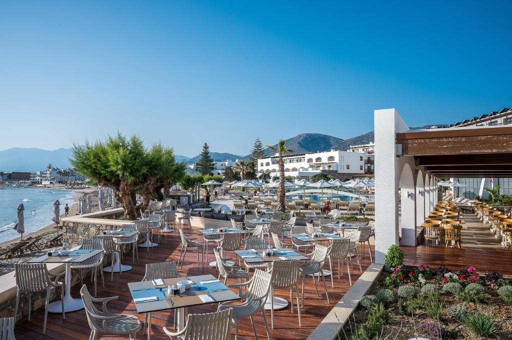 Restorāna terase piekrastē Creta Maris Resort, ar ēdināšanas galdiem un pludmali.