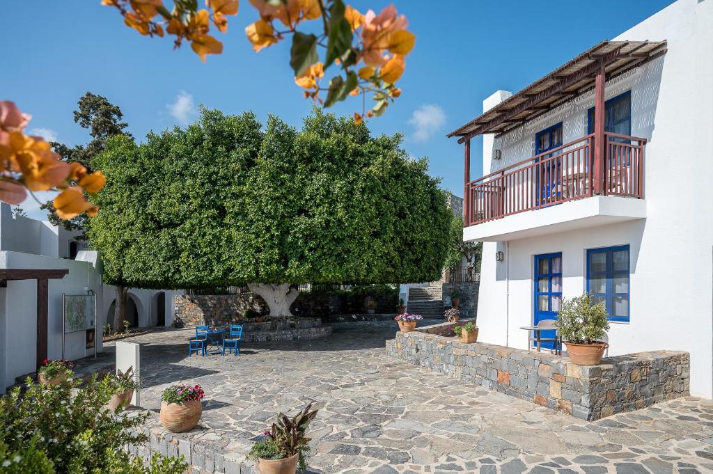 Creta Maris Resort pievilcīgs pagalms ar zaļu koku un akmens bruģi