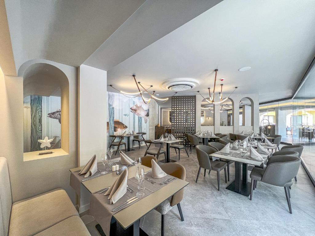 Mūsdienīgs restorāna interjers ar elegantiem galdiem un krēsliem, sienas rotā jūras tematikas gleznojumi. Silta atmosfēra un izsmalcināti galda klājumi.