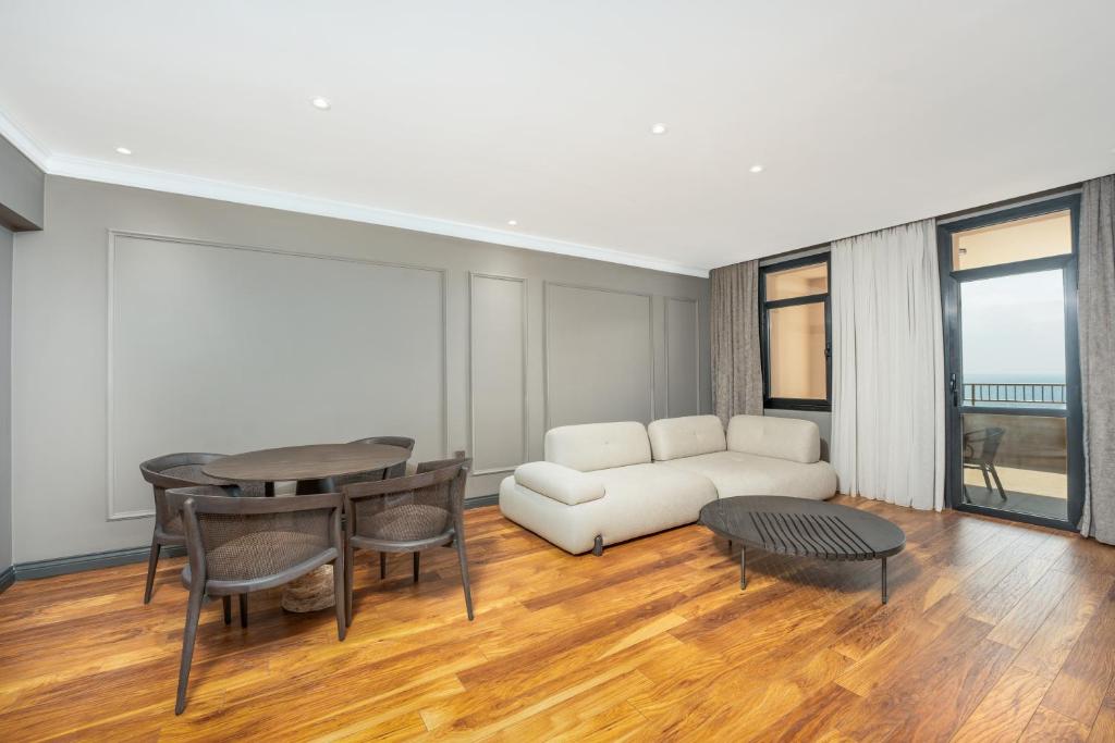 Mūsdienīgs viesnīcas numurs Adora Hotel & Resort ar ērtu dīvānu un ēdamgaldu.