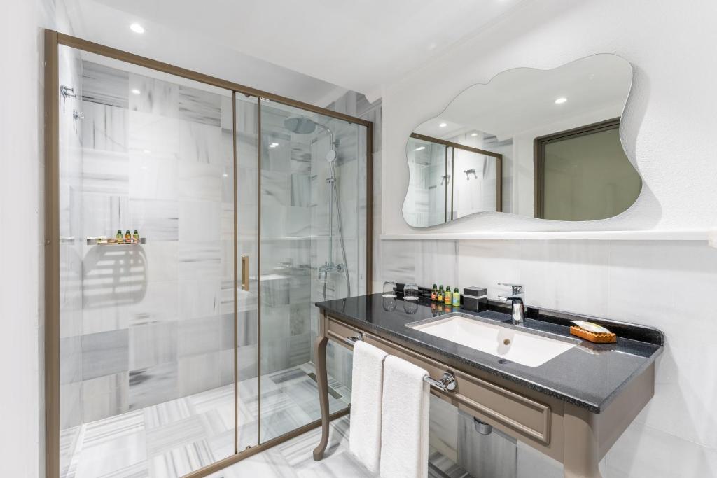 Mūsdienīga vannas istaba Adora Hotel & Resort ar stikla dušu un melnu akmens izlietni.