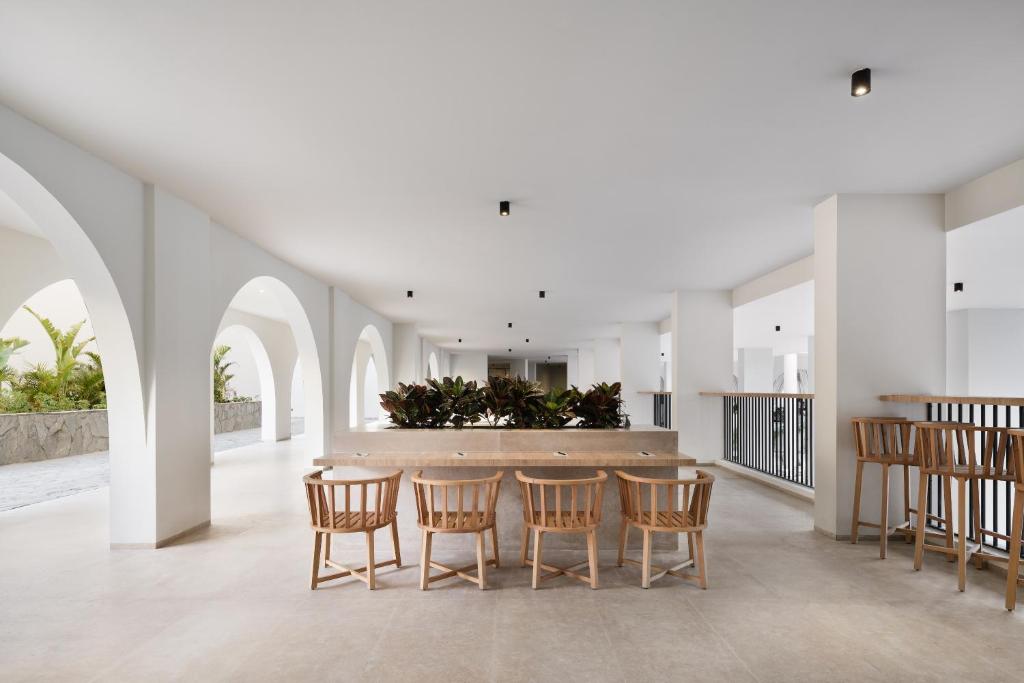 Gaiša un moderna atpūtas zona Serry Beach Resort ar koka krēsliem.