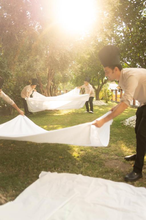 Darbinieki izplata baltus galdautus pie Castival Hotel dārzā.