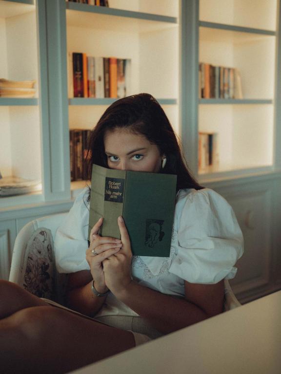 Jauna sieviete lasot grāmatu pie Castival Hotel plauktiem