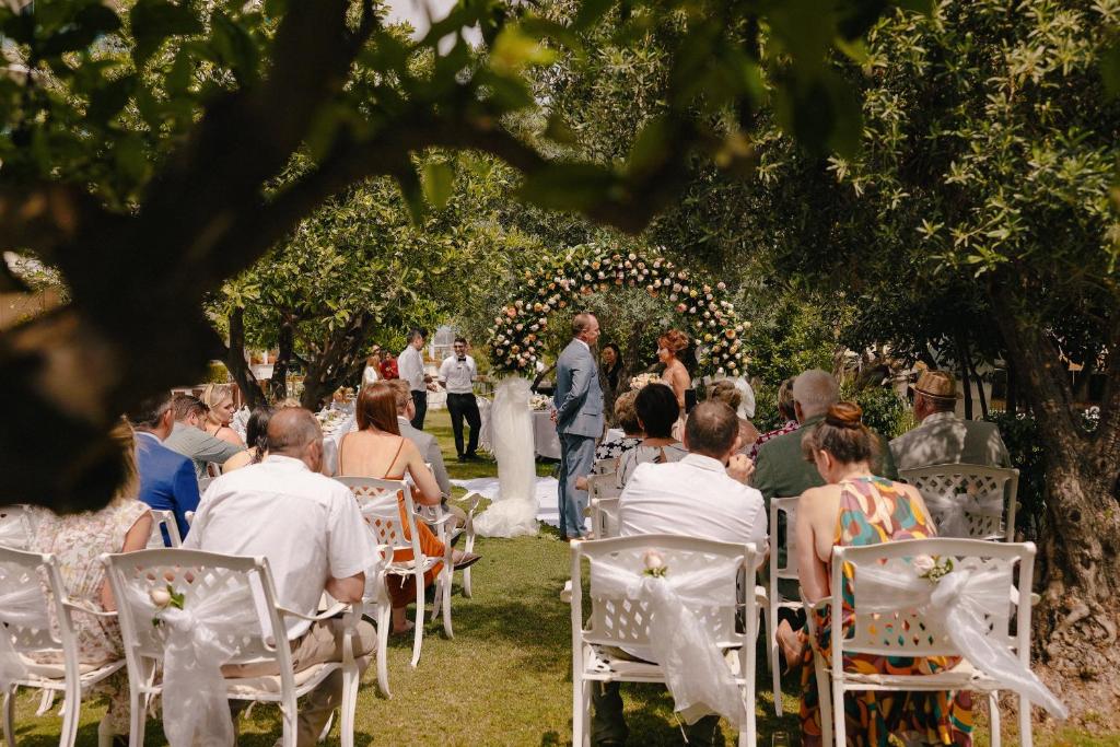 Kāzu ceremonija Castival Hotel dārzā ar ziedu arku.