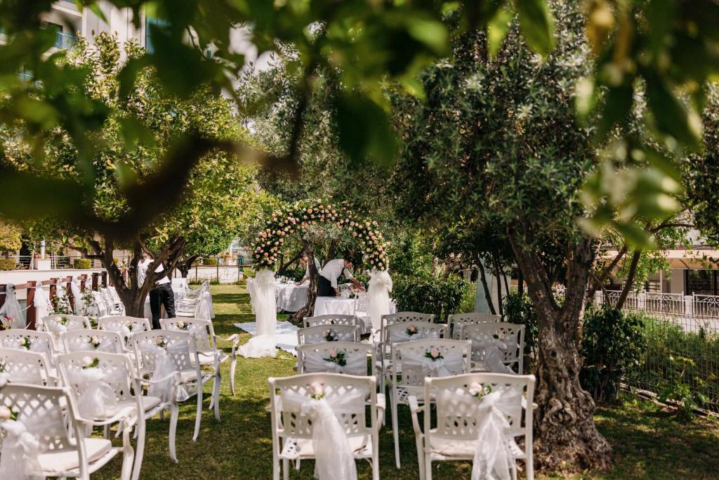 Kāzu ceremonija dārzā pie Castival Hotel, ar ziedu arku un sēdvietām.