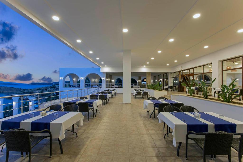 Restorāns ar terasi pie jūras Holiday Inn Resort Bodrum, saulrieta gaismā.
