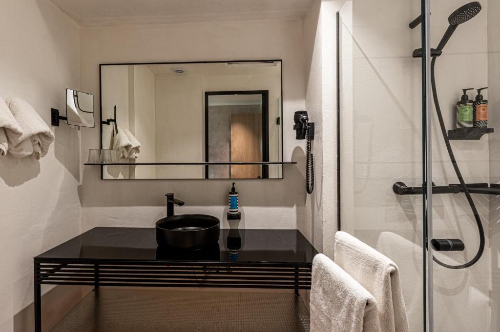 Mūsdienīgs vannas istabas dizains ar melnu izlietni un spoguli, kas atspoguļo elegantu interjeru un vannas piederumus.