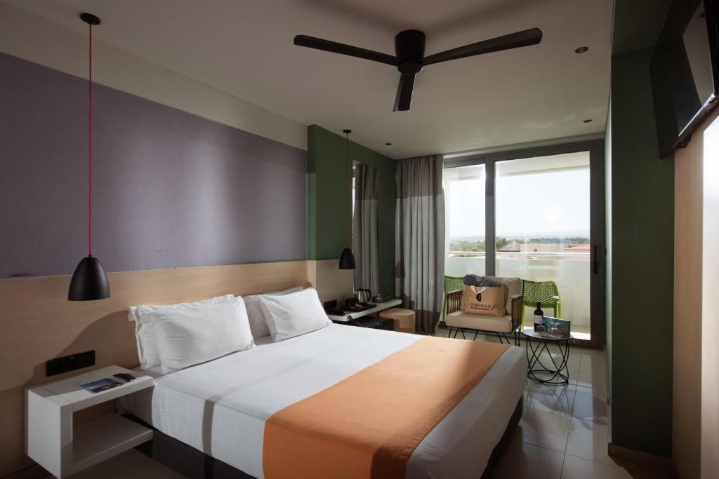 Mūsdienīga viesnīcas numura interjers ar dubultgultu, stilīgu apgaismojumu un balkonu. Numurā ir ērtas sēdvietas un skats uz ārpusi.