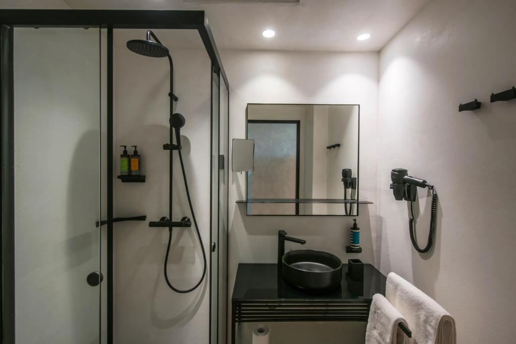 Mūsdienīgs vannas istabas interjers ar dušu, melnu izlietni un spoguli. Svaigu toņu šampūni un dvieļi pieejami uz plaukta.