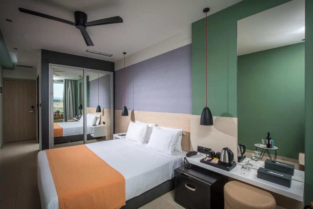 Mūsdienīga viesnīcas numura interjers ar baltiem gultas veļas komplektiem un oranžu gultas pārklāju. Numurā redzams liels spogulis, melni gaismas ķermeņi un kafijas pagatavošanas stacija.