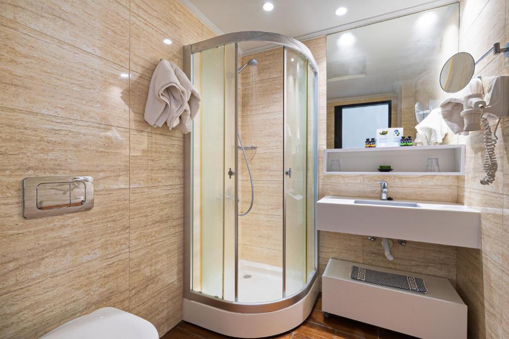 Mūsdienīga vannas istaba ar dušas kabīni, pelēkām flīzēm un minimālistisku dizainu, kas apvieno funkcionalitāti un estētiku.