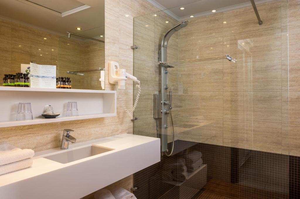 Mūsdienīga un eleganta vannas istaba ar stikla dušu, modernām santehnikas iekārtām un dekoratīvām kosmētikas precēm. Vannas istabā ir gaišas krāsas akmens apdare un plaša izlietne.