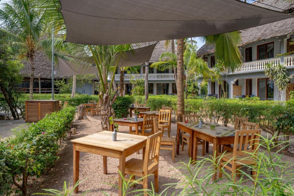 Michamvi Sunset Bay restorāna āra terase ar ēnām un tropu augiem.