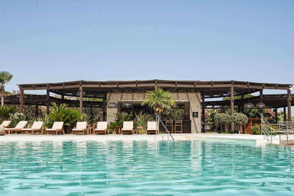 Lindian Village Beach Resort Rhodes, Curio Collection by Hilton baseins ar sauļošanās krēsliem