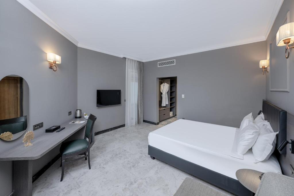 Moderns numurs Adora Hotel & Resort ar ērtu gultu un rakstāmgaldu.