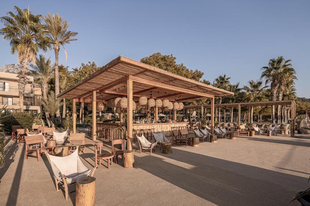 Balmy Beach Resort Kemer pludmales bārs ar palmām un komfortablām sēdvietām.