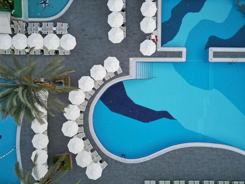 Aydinbey Famous Resort baseins ar sauļošanās krēsliem piekrastē