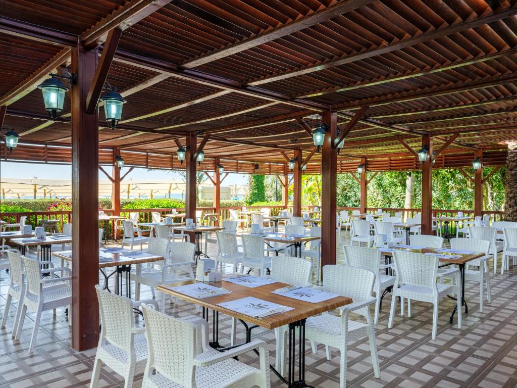 Aydinbey Famous Resort āra restorāns ar baltiem galdiem un krēsliem