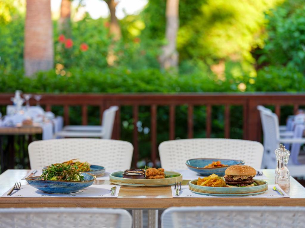 Gards ēdiens uz galda pie Aydinbey Famous Resort, iekļaujot burgeru un salātus.