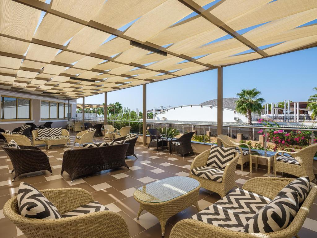 Aydinbey Famous Resort terase ar moderniem mēbeļiem un palmām.