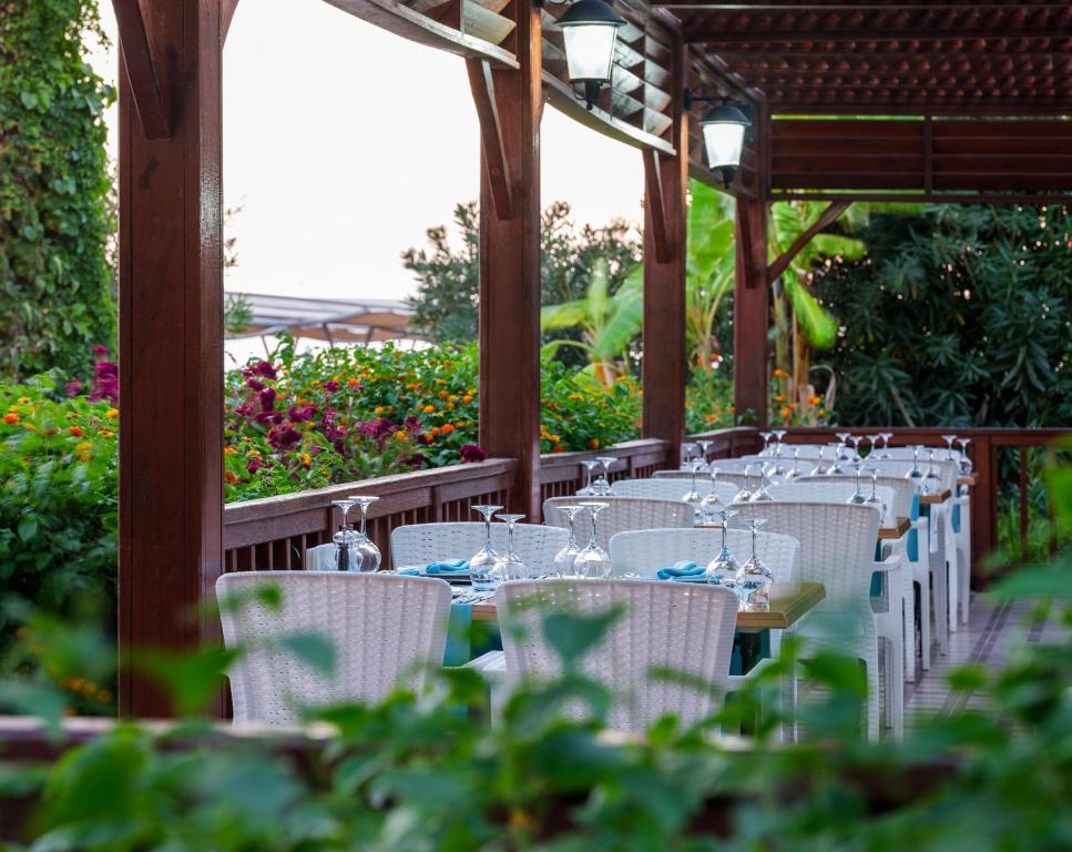 Aydinbey Famous Resort terase ar galdiem un ziedu dārzu