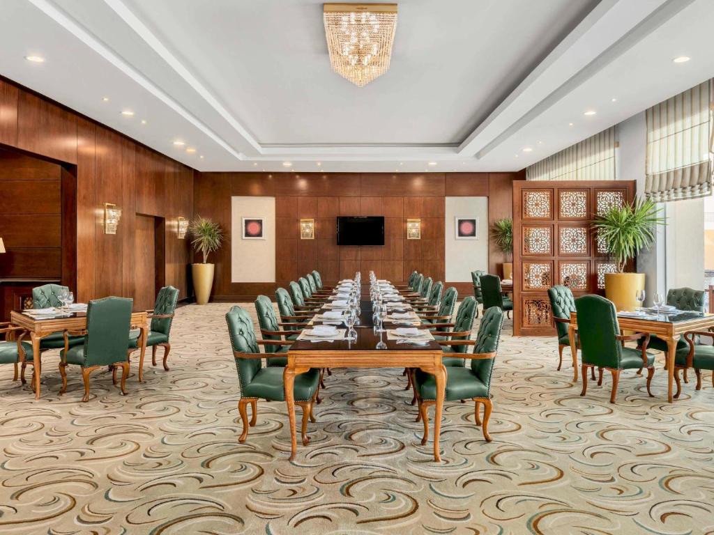 Konferenču zāle Rixos Sharm El Sheikh ar elegantiem galdiem un krēsliem.