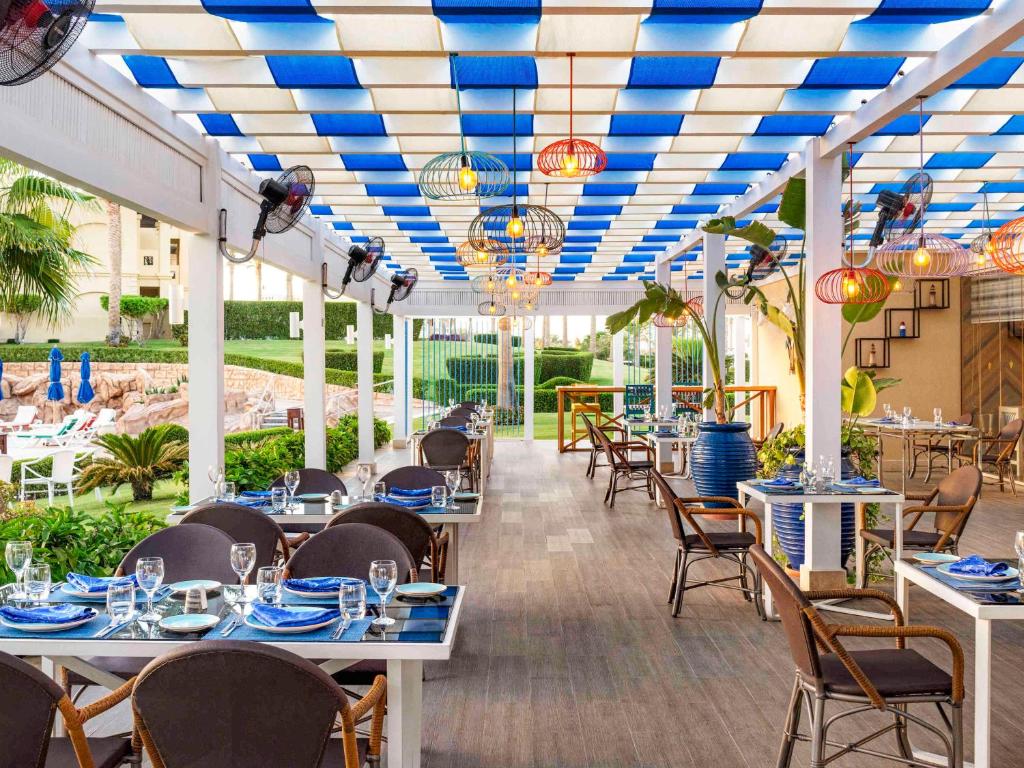 Rixos Sharm El Sheikh ērta restorāna iekārtojums ar zilu jumtu un dārzu skatu.