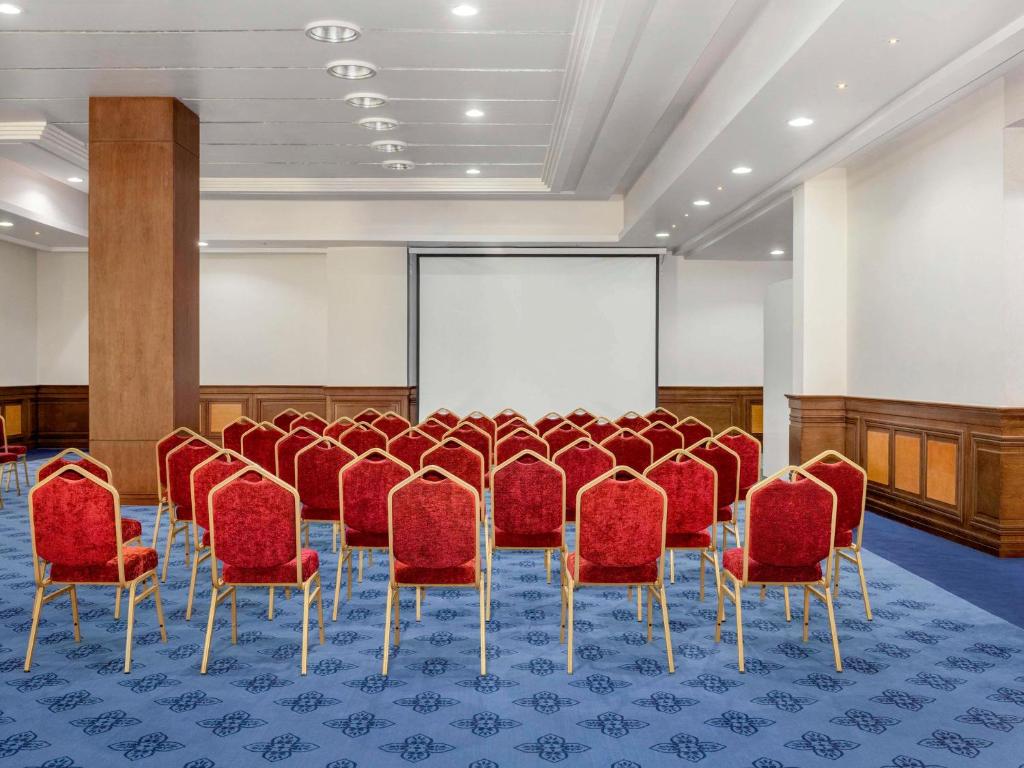 Rixos Sharm El Sheikh konferenču zāle ar sarkaniem krēsliem un projektoru