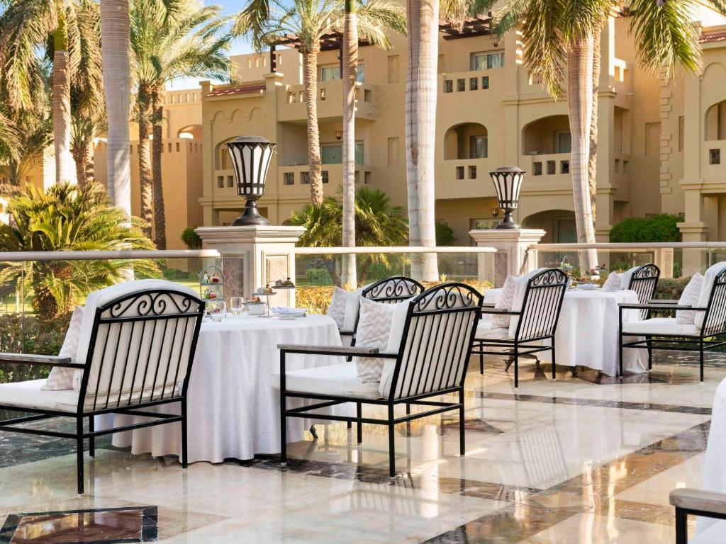 Āra restorāns pie Rixos Sharm El Sheikh ar palmām un elegantām galdiem.