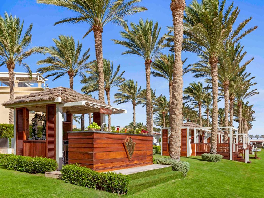 Rixos Sharm El Sheikh atpūtas zona ar palmu kokiem un pludmales bāru.