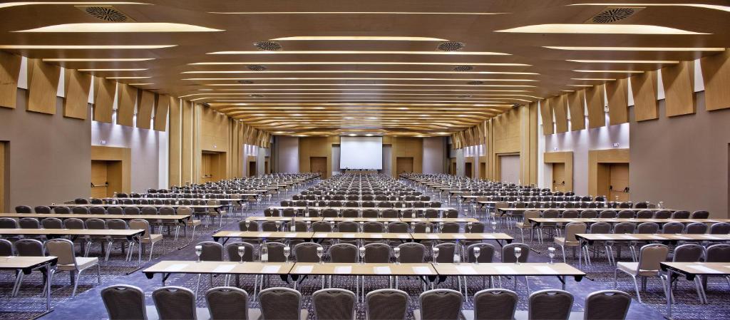 Liela konferences telpa ar rindu galdiem un krēsliem, sagatavota pasākumam. Telpas dizains iekļauj modernus elementus un plašu apgaismojumu.