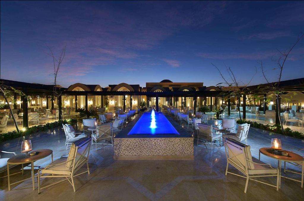 Steigenberger Alcazar piekrastē ar vakara izgaismojumu un peldbaseinu.