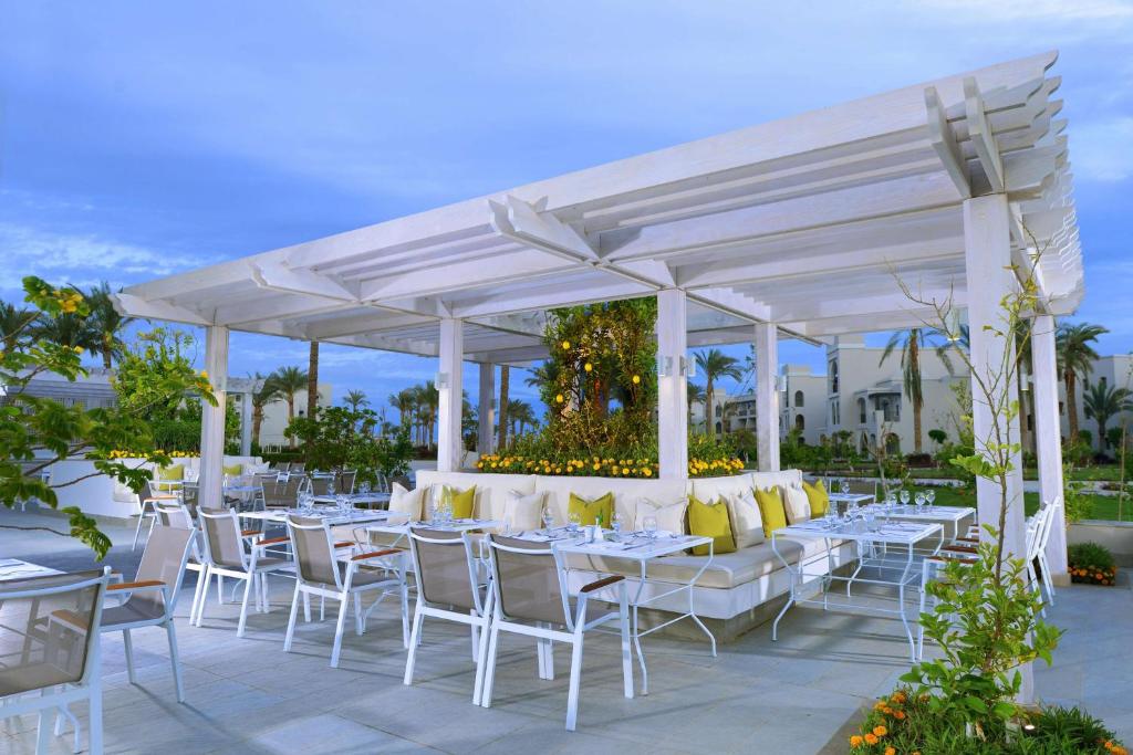 Atvērta terase pie Steigenberger Alcazar ar dārza mēbelēm un palmām.