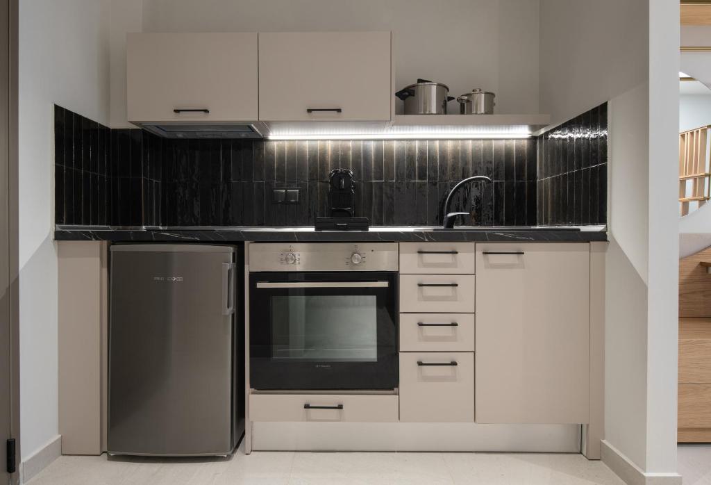 Mūsdienīga virtuve ar melnu flīžu akcentiem un moderniem iekārtām, tostarp ledusskapi un cepeškrāsni. Ideāla izvēle kompakta dzīvojamā telpā.