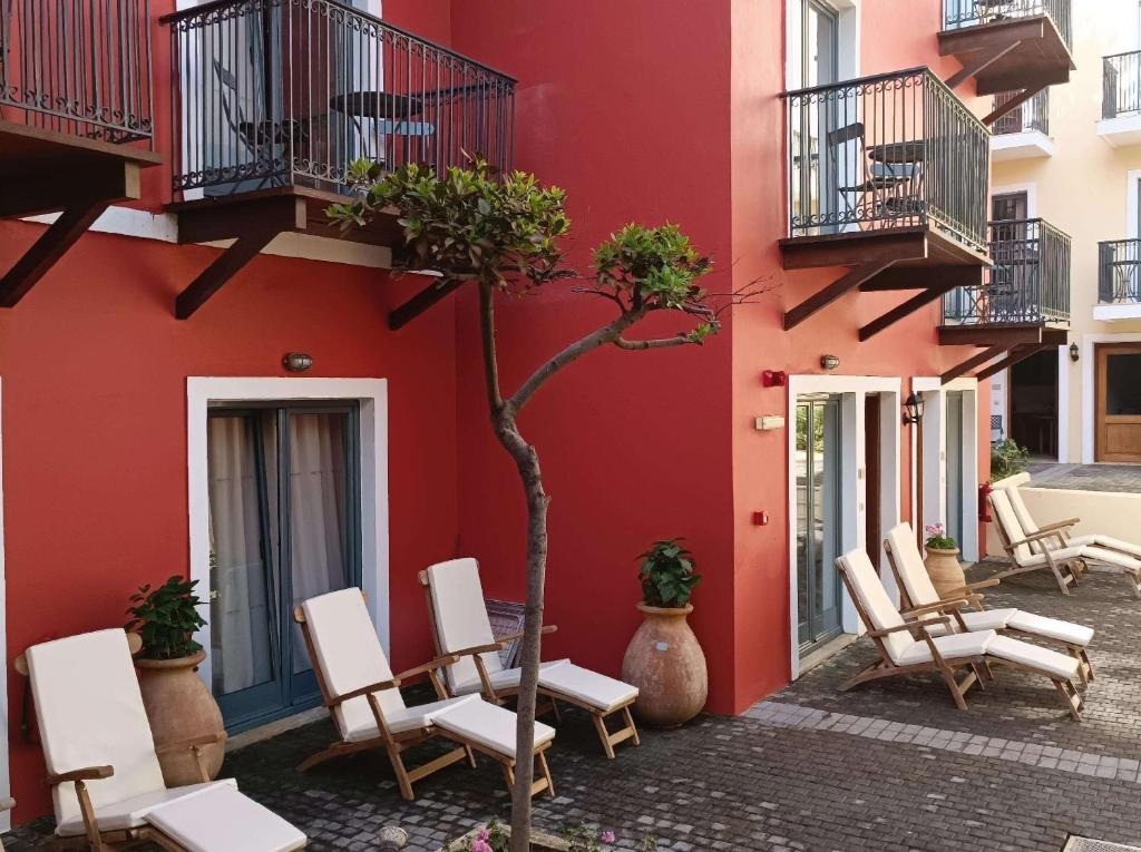 Grecotel Plaza Beach House dārza zona ar saulessargiem un balkoniem.