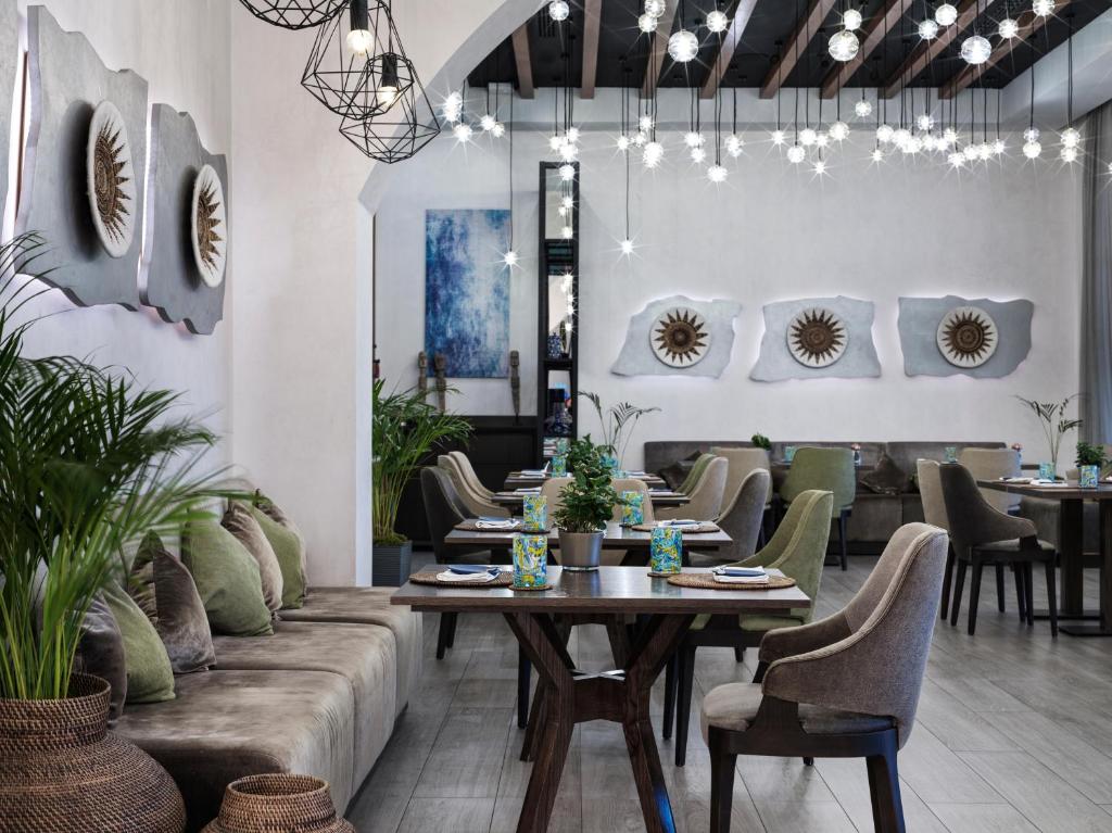 Mūsdienīgs restorāns ar stilīgu interjeru, kurā redzami mākslas darbi un augu kompozīcijas, piedāvā patīkamu atmosfēru un elegantu galdu klājumu.