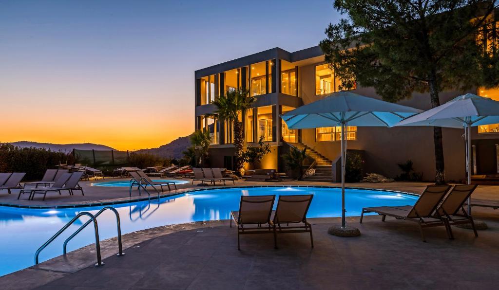 Šī viesnīca White Olive Premium Lindos pievilcīgs baseins ar saules krēsliem saulrietā.