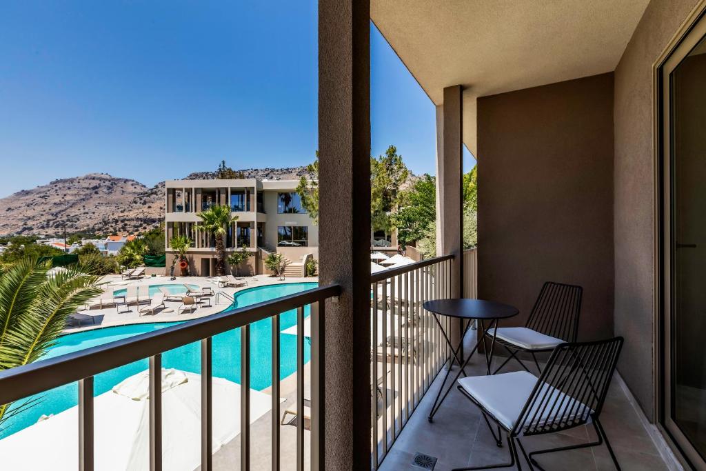 Skats no White Olive Premium Lindos balkona uz baseinu un kalniem.