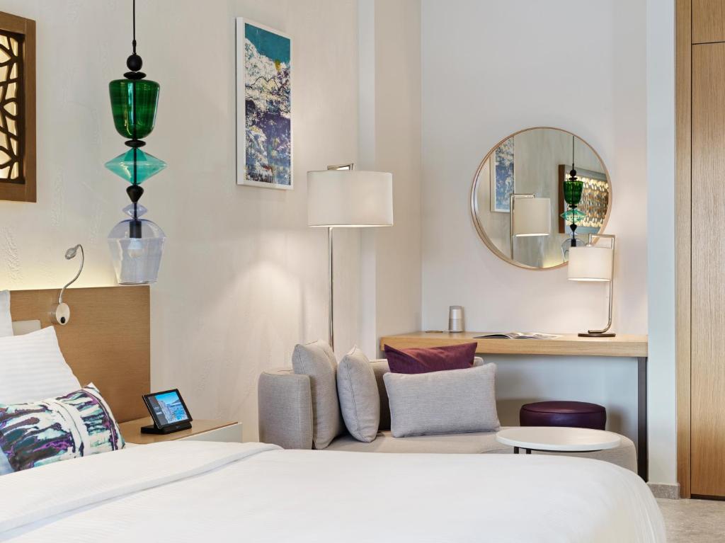 Mūsdienīgs viesnīcas numurs ar ērtu gultu, stilīgu apgaismojumu un elegantu interjeru. Iekārtojums ietver dīvānu, rakstāmgaldu un dekoratīvas gleznas.