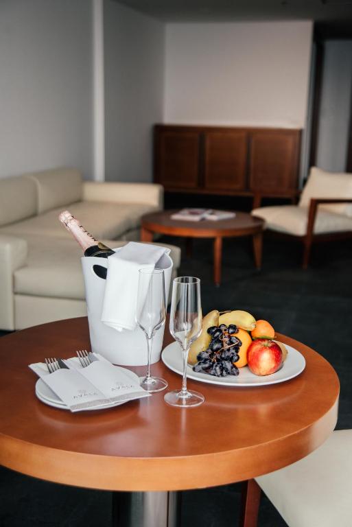 Svaiga augļu plate ar šampanieti un glāzēm, novietota uz koka galda viesnīcas interjerā. Eleganta atmosfēra un relaksējošs dizains.