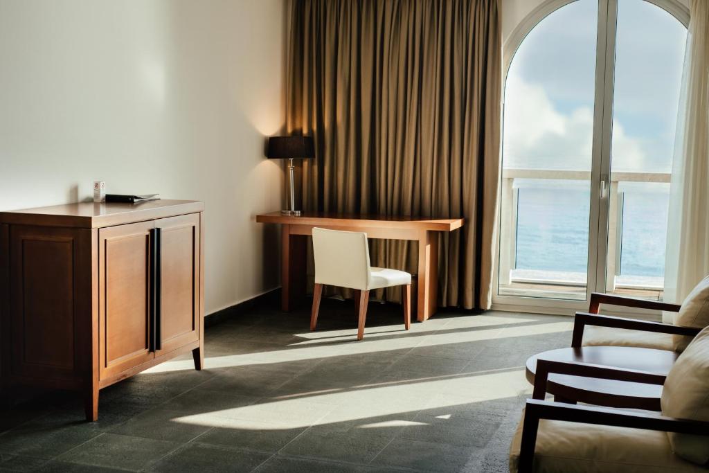 Mūsdienīgs viesnīcas numurs ar koka mēbelēm, rakstāmgaldu un skatu uz jūru. Gaisīgs interjers ar dabiskiem apgaismojumiem un elegantiem aksesuāriem.