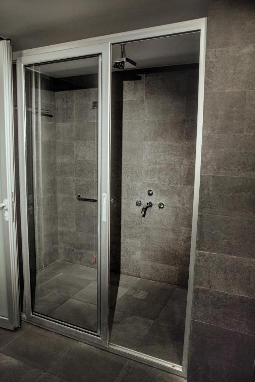 Mūsdienīga duša ar caurspīdīgiem stikla durvīm, pelēkām flīzēm un hromētiem santehnikas elementiem. Šī telpa ir eleganta un funkcionāla, ideāli piemērota mūsdienu vannasistabai.