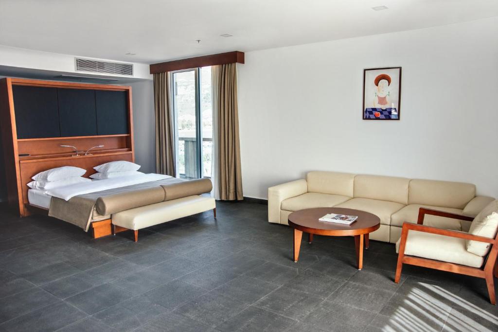 Mūsdienīga viesnīcas numura interjers ar gultu un ērtu atpūtas zonu, kurā ir dīvāns un kafijas galds. Logi nodrošina dabisko apgaismojumu un skatu uz ārpusi.