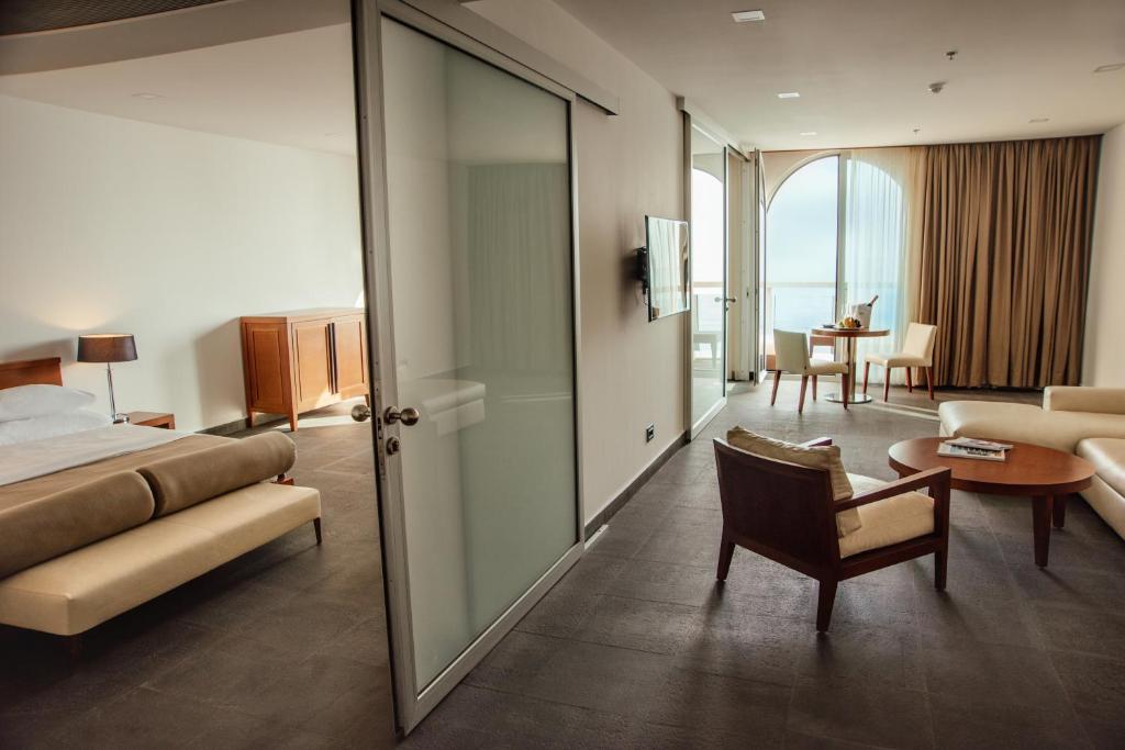 Mūsdienīgs viesnīcas numurs ar atvērtu plānojumu, kurā ir guļamistaba, dzīvojamā zona un lieli logi, kas nodrošina dabīgu apgaismojumu. Interjers apvieno komfortu un eleganci.