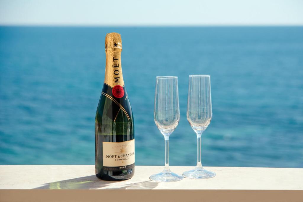 Šampanieša pudele ar divām glāzēm pie jūras. Ideāls brīdis svinībām un relaksācijai.